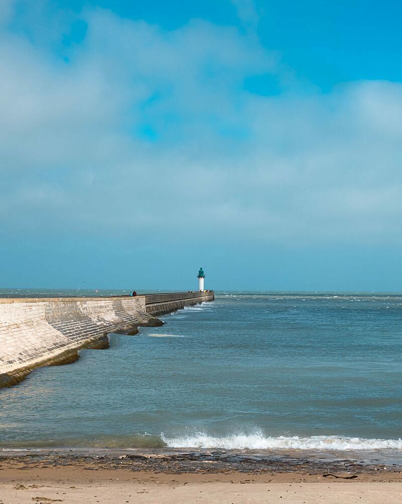 A view of the sea and pier near Calais Port on the Côte d'Opale, a scenic location for travelers waiting for ferry crossing.