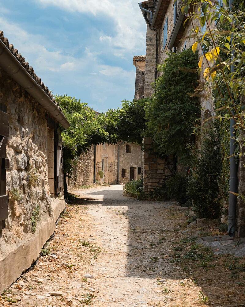 A charming narrow stone alley with lush greenery in the medieval village of Lagorce near Les Castels 5-star estate campsites in Ardèche.