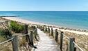  A scenic wooden boardwalk with rope railings cutting through sand dunes, near a luxury Les Castels campsite