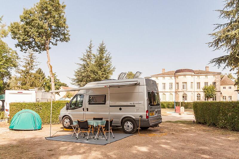 une tente et un camping car devant un château