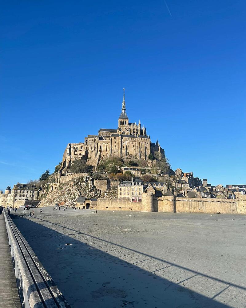 A clear daylight view of the historic abbey of Mont Saint-Michel in Normandy, a famous landmark accessible from Les Castels 5-star campsites in France, showcasing the surroundings of premium campsites France.