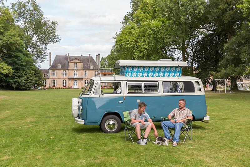 Deux personnes devant un van dans un camping au château