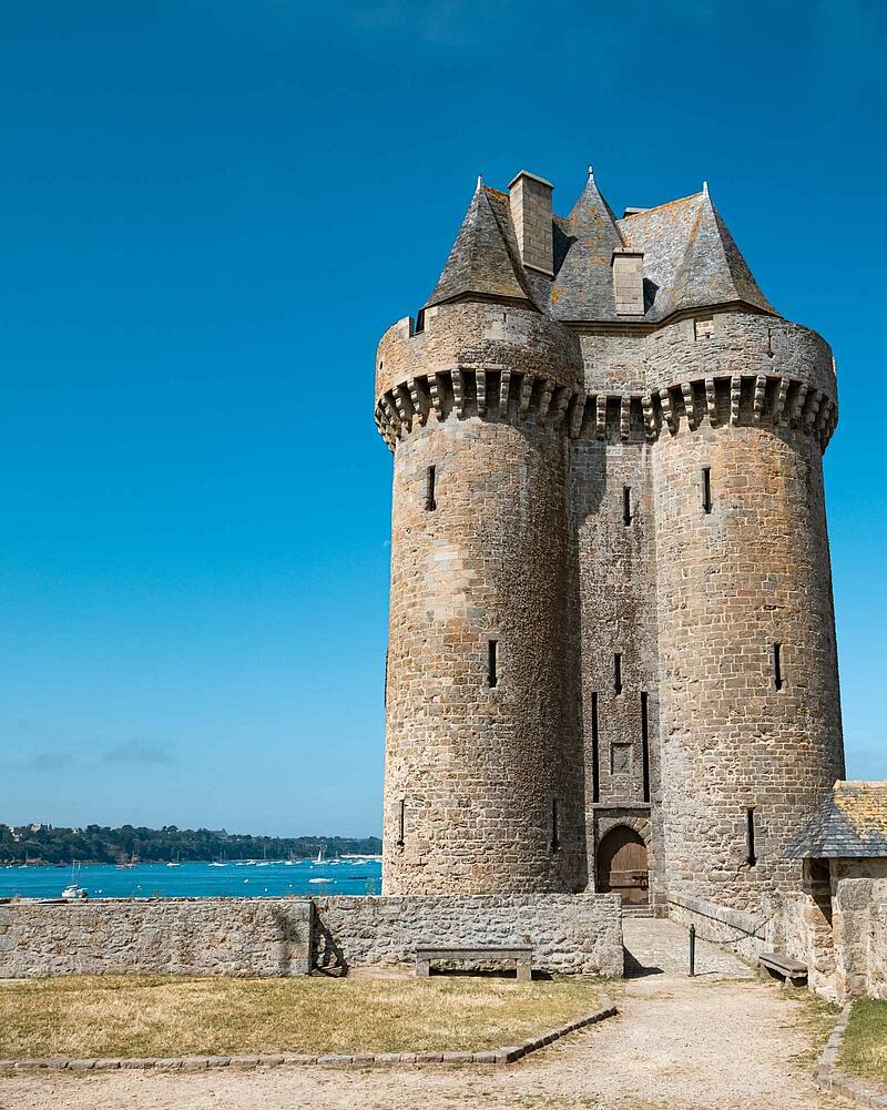 View of the Solidor Tower, a fortified stone keep located on the waterfront under a cloudless blue sky in Saint-Malo.